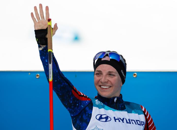 nordische skifahrerin lächelt und winkt 