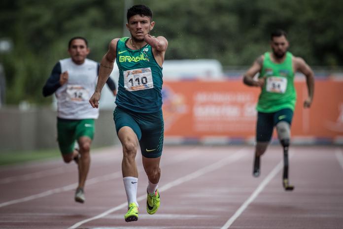 Three athletes running on an athletics track