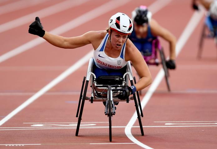 a female wheelchair racer punches the air as she crosses the line