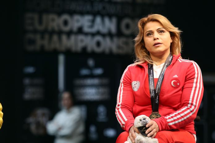 a female powerlifter with her gold medal on the podium