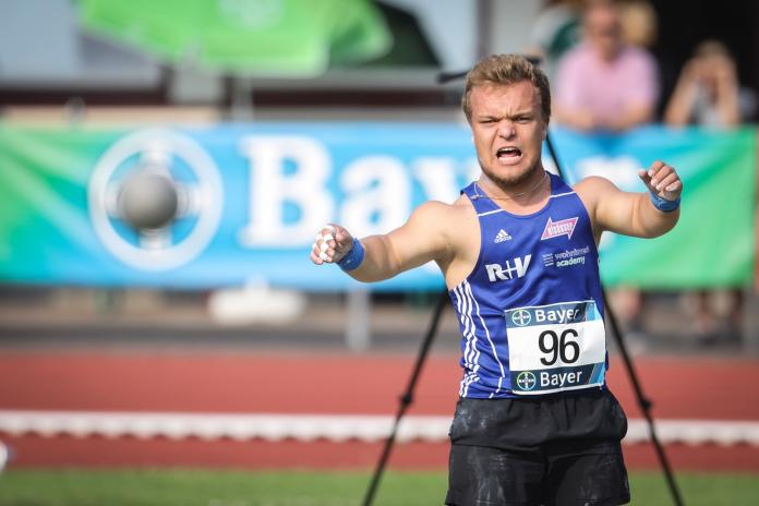 a male thrower of short stature launches a shot put