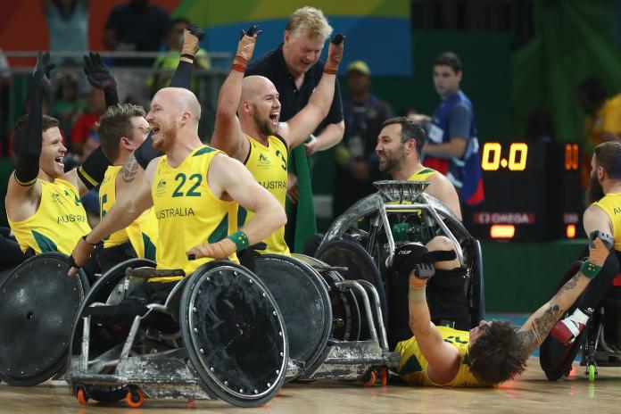 a group of male wheelchair rugby players celebrating on the court