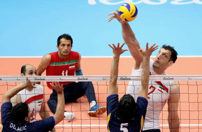 a male sitting volleyball player attempts a block