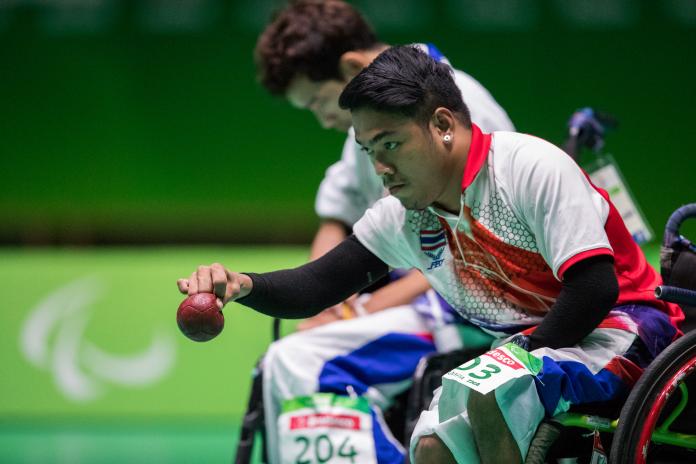 Man in a wheelchair throwing a red boccia ball