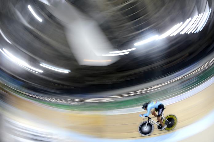 Man on track cycle rides around a velodrome