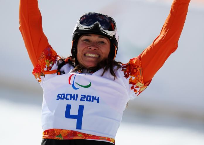 female Para snowboarder Bibian Mentel-Spee raises her arms in celebration on the slope