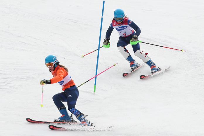 female Para alpine skier Menna Fitzpatrick follows her guide through a slalom gate