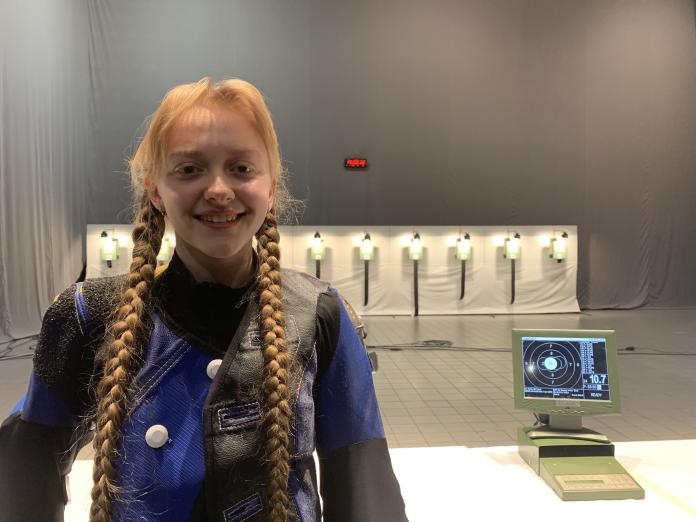 female Para shooter Iryna Shchetnik smiling in front of a row of targets