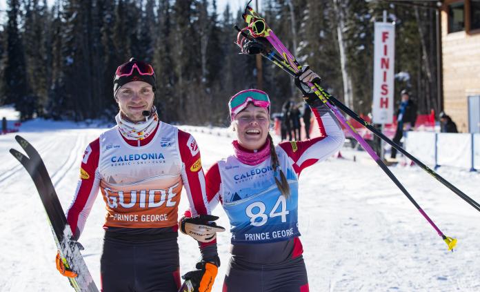 female vision impaired skier Carina Edlinger and her male guide raise their arms in celebration