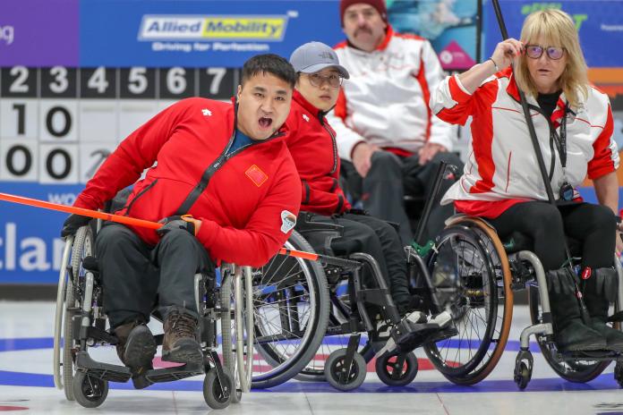 Chinese male wheelchair curler reacts as he releases his stone