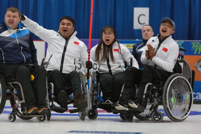 Three Chinese wheelchair curlers celebrate expressively on the ice