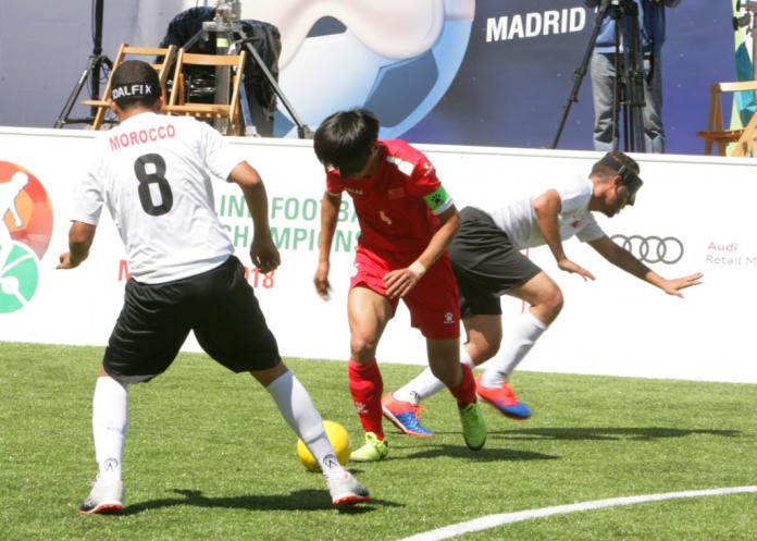 Chinese blind soccer player Wei Jiansen dribbles past a Moroccan defender preparing to shoot