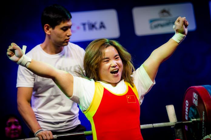 A woman in a wheelchair celebrating with a man behind her pushing her chair