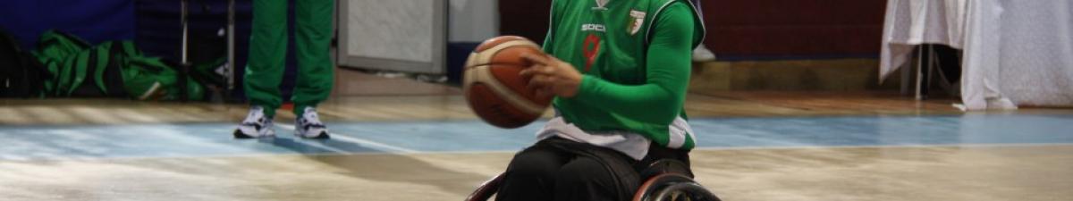 Woman wearing a hijab shooting a basketball in a wheelchair