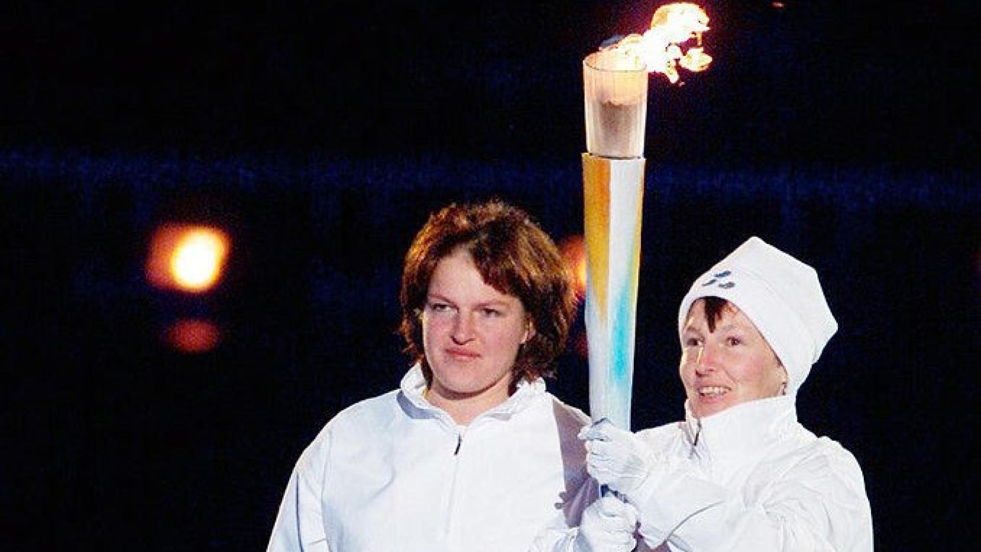 Two people are holding a torch together during the Salt Lake City 2002 Opening Ceremony