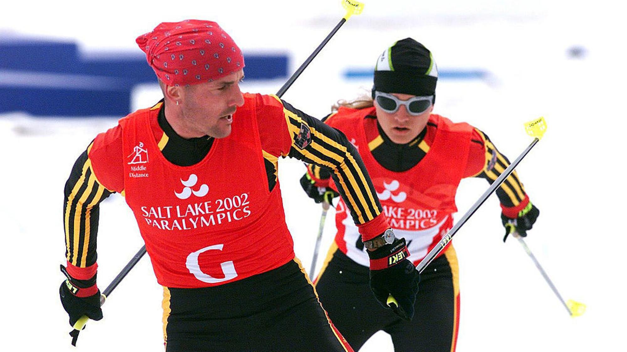 A female skier is competing behind a sighted guide