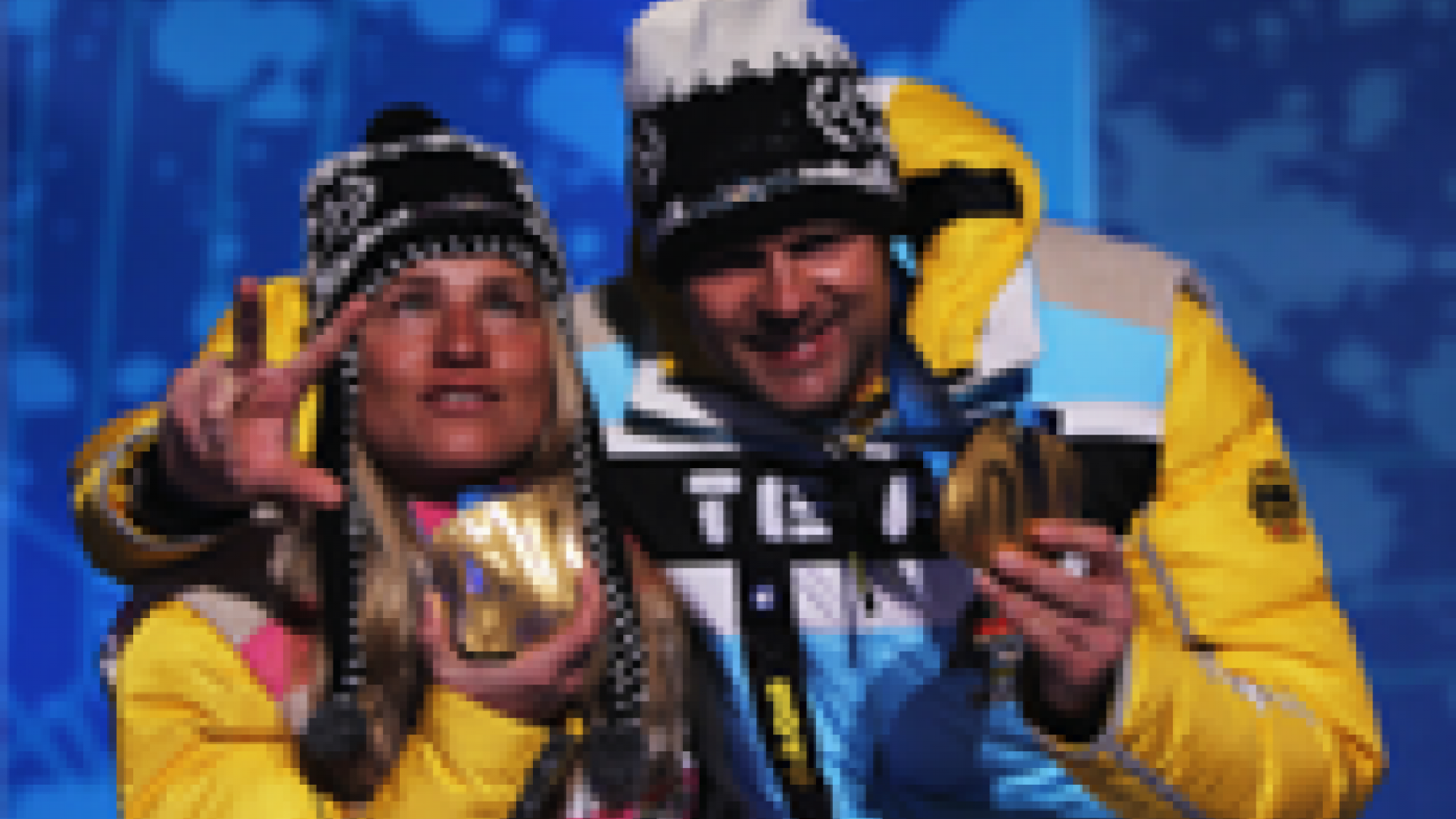 A picture of a woman showing her gold medal with a man during a medal ceremony