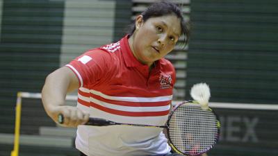 a female Para badminton player in a wheelchair plays a backhand shot
