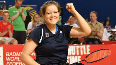 a female Para badminton player in a wheelchair punches the air in celebration