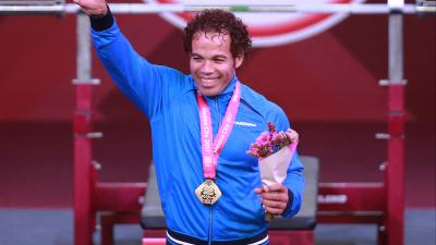 a male powerlifter celebrates his gold medal on the podium