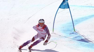 a male Para alpine skier rounds a gate