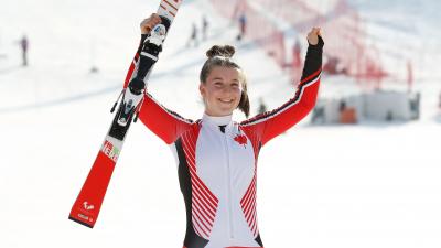 a female Para skier raises her arms in celebration