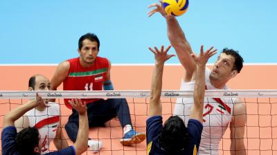 a male sitting volleyball player attempts a block