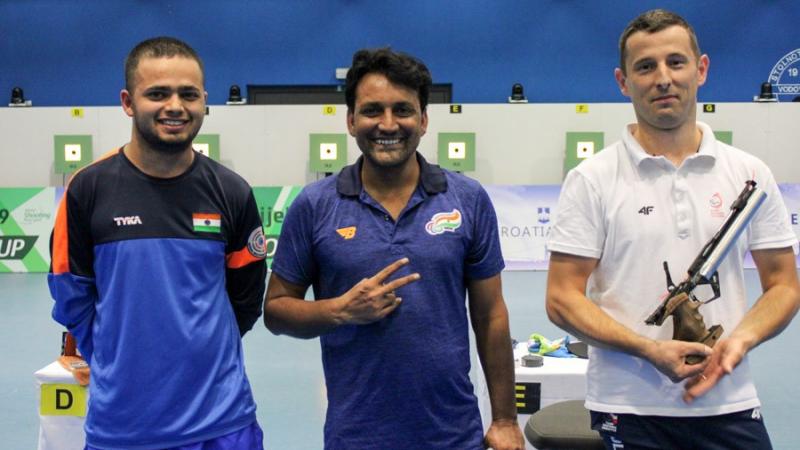 Three male pistol shooters pose for a photo