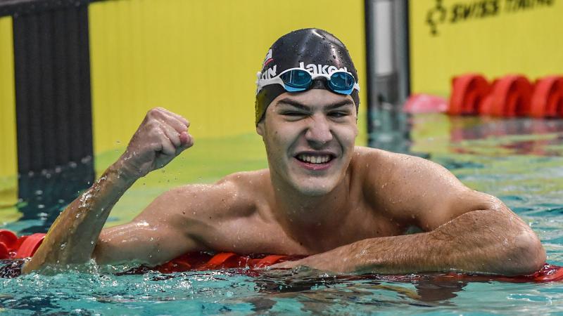 a male swimmer in the water giving a victory fist pump