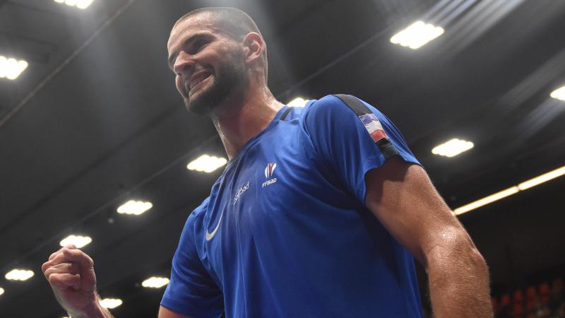 a male Para badminton player clenches his fist in celebration