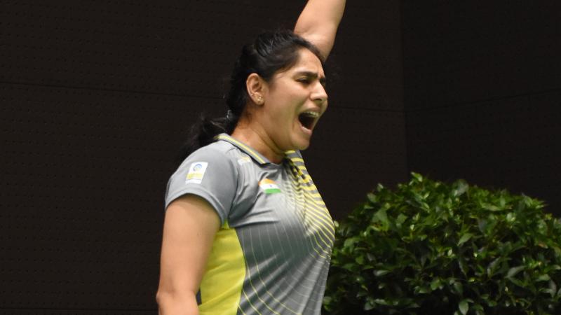 a female Para badminton player with a prosthetic leg punches the air