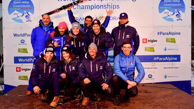 a group of Para alpine skiers standing and sitting