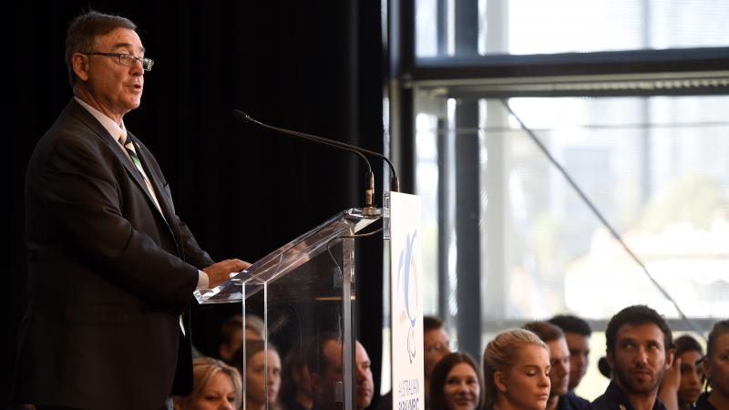 a man standing at a podium giving a speech while the audience watches