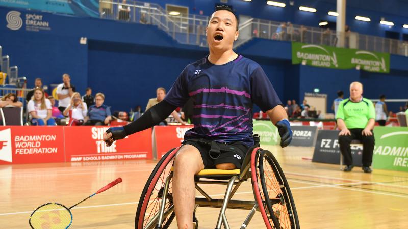 a male Para badminton player in a wheelchair cheers after scoring a point