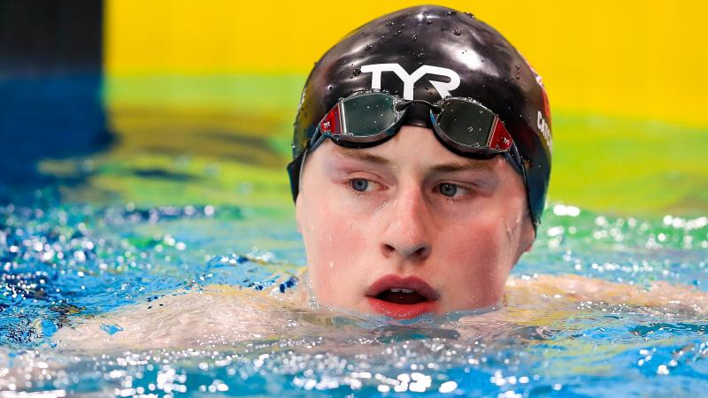 a male Para swimmer in the water at the end of a race