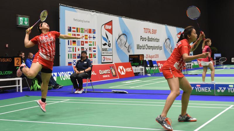 Pair of female Indonesia badminton athletes play on the court