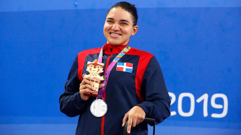 female Para swimmer holds up her silver medal on the podium
