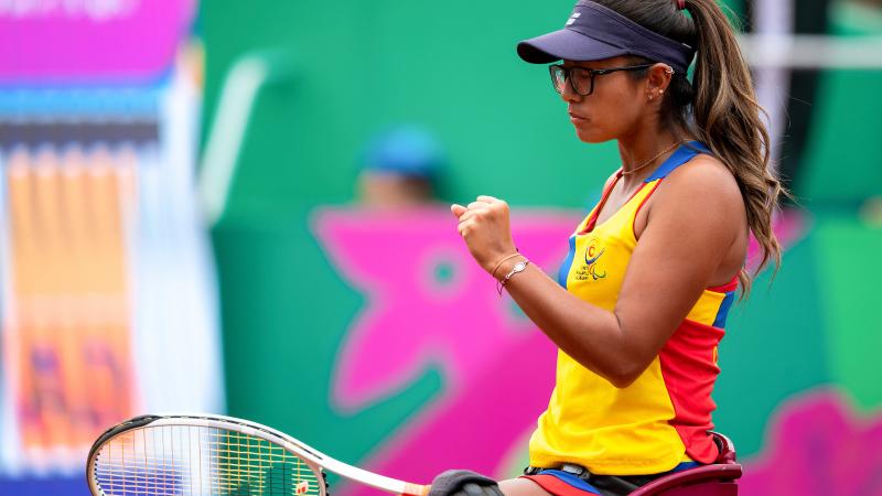 a female wheelchair tennis player clenches her fist on the court