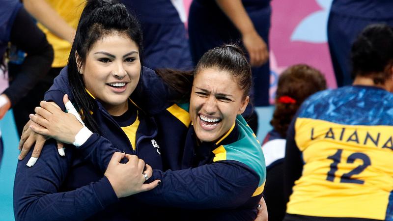 two female sitting volleyball players hugging