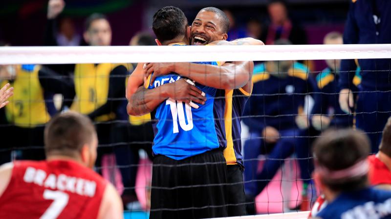 male sitting volleyball players celebrate on the court