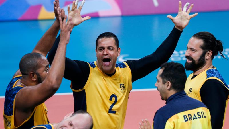 male sitting volleyball players celebrate on the court
