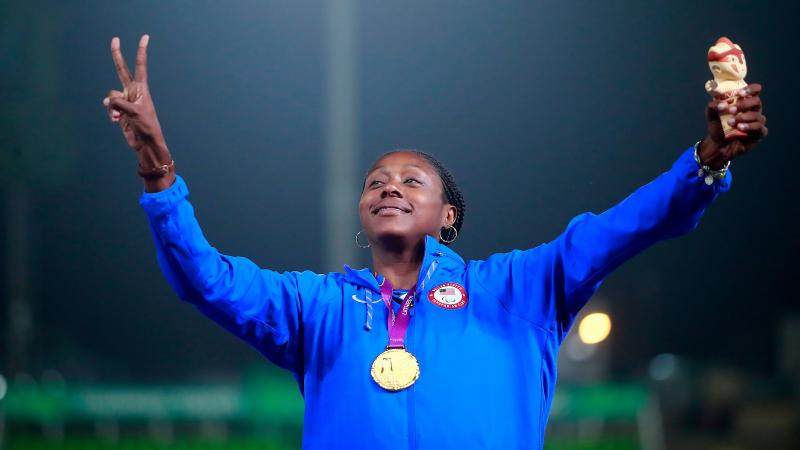 a female Para athlete giving a victory hand gesture on the podium