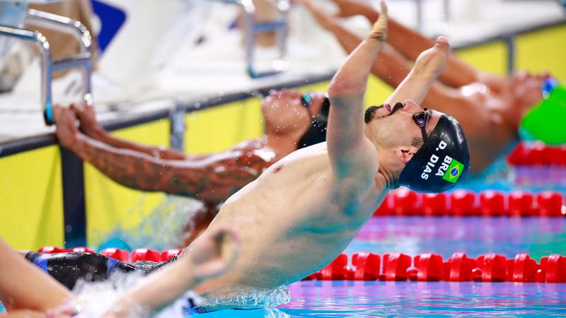 a male Para swimmer jumps backwards into the water