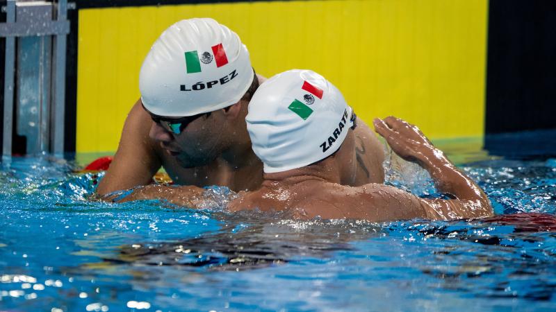 two male Para swimmers hugging over the lane rope