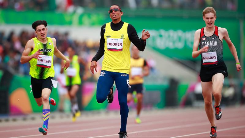 three male Para athletes running to the finish line