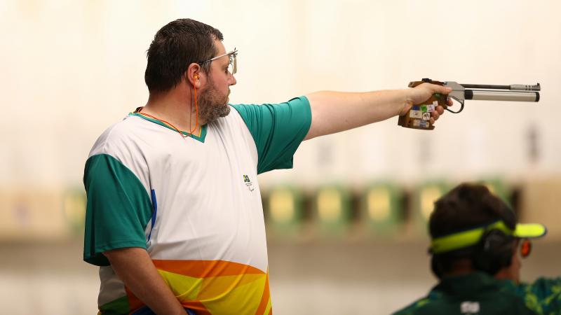 a male Para shooter points a pistol at a target