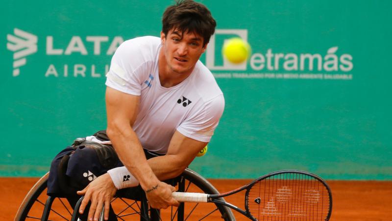 a male wheelchair tennis player plays a forehand