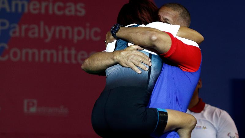 a female powerlifter with no legs hugging her coach