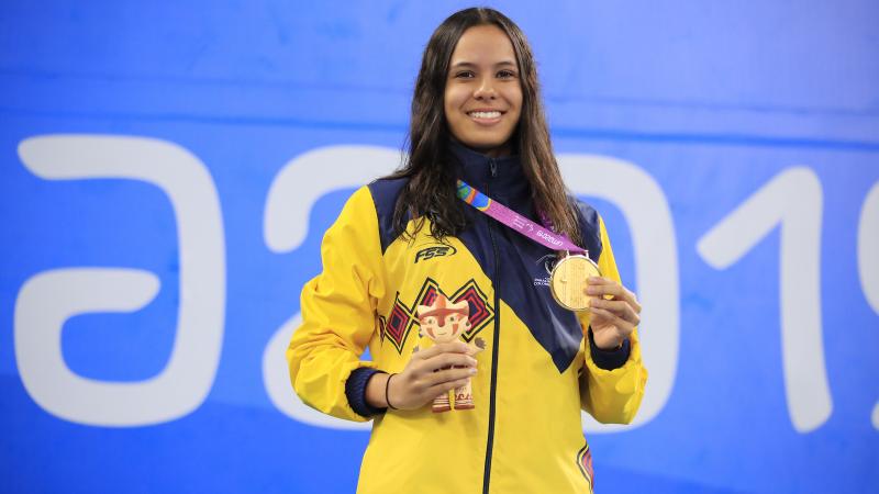 female Para swimmer on the podium holding her gold medal