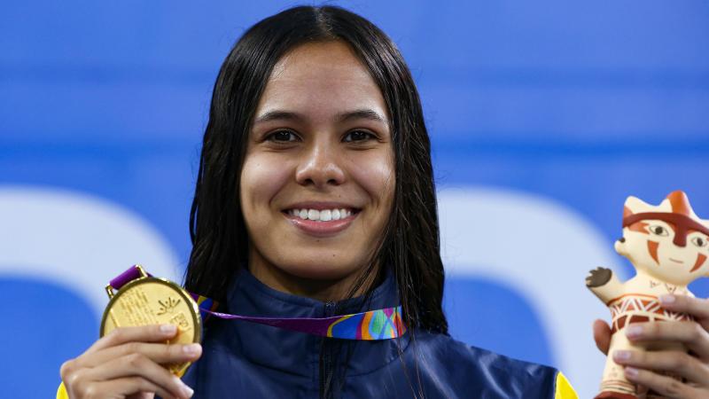 a female Para swimmer holding up her gold medal